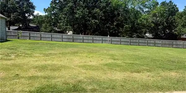Image 2: Expansive lot featuring a wood privacy fence and m