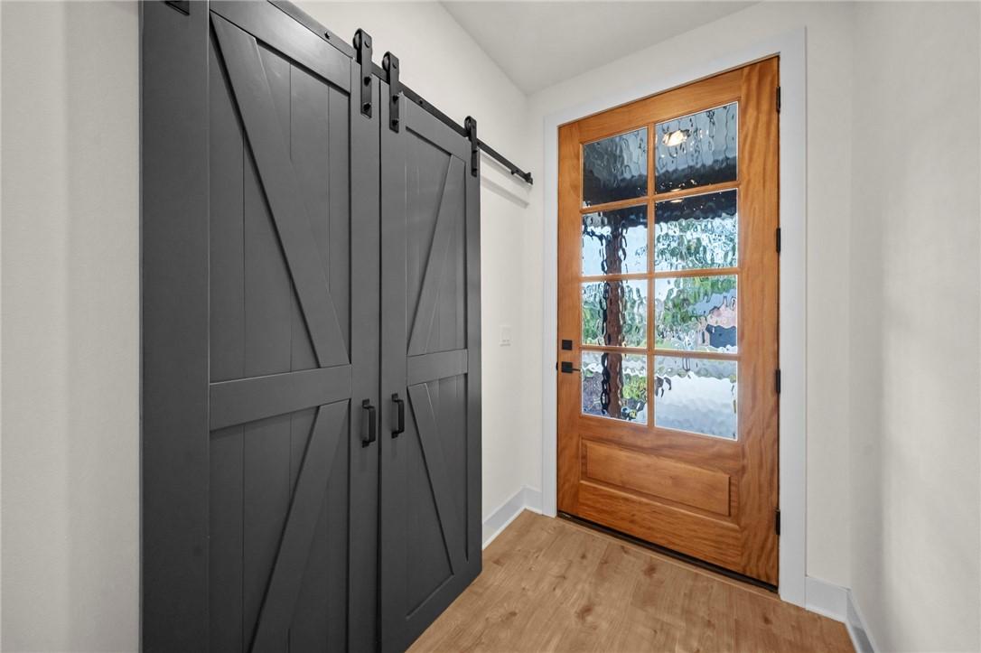 Image 2: Entryway featuring a natural wood-finish front doo
