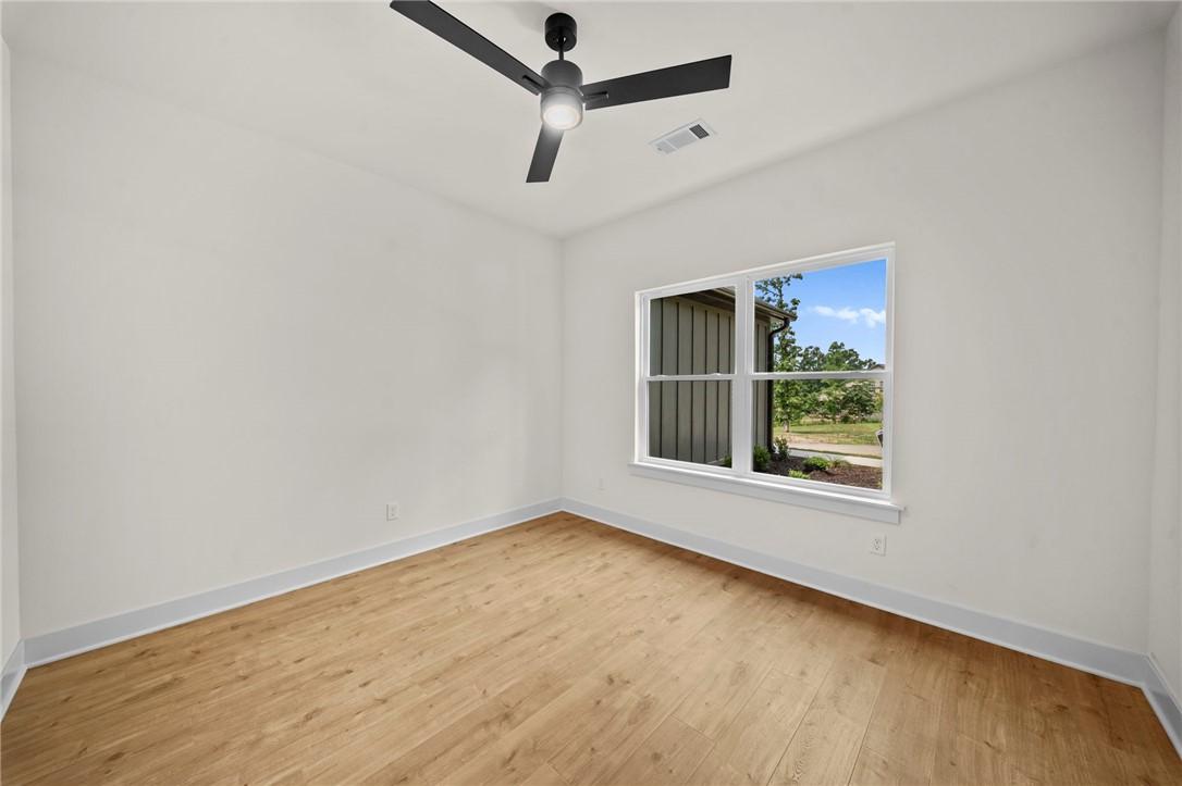 Image 4: Spacious room featuring wood-finish flooring, whit