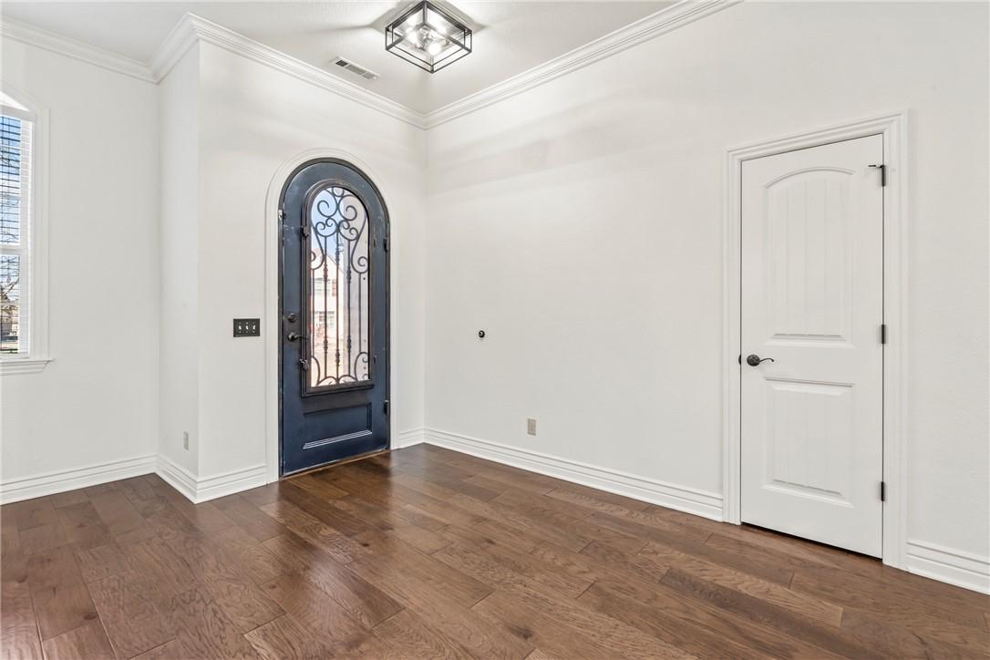 Image 3: Entrance foyer featuring a dark arched door with o