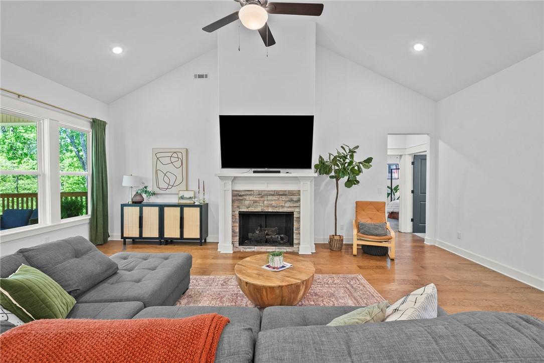 Image 2: Vaulted ceiling living area featuring a stone-surr