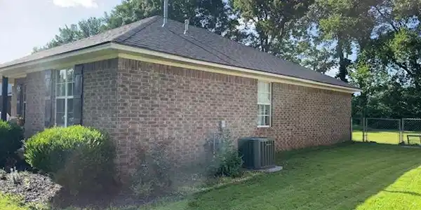 Image 3: Brick exterior with a dark-shingled roof and light
