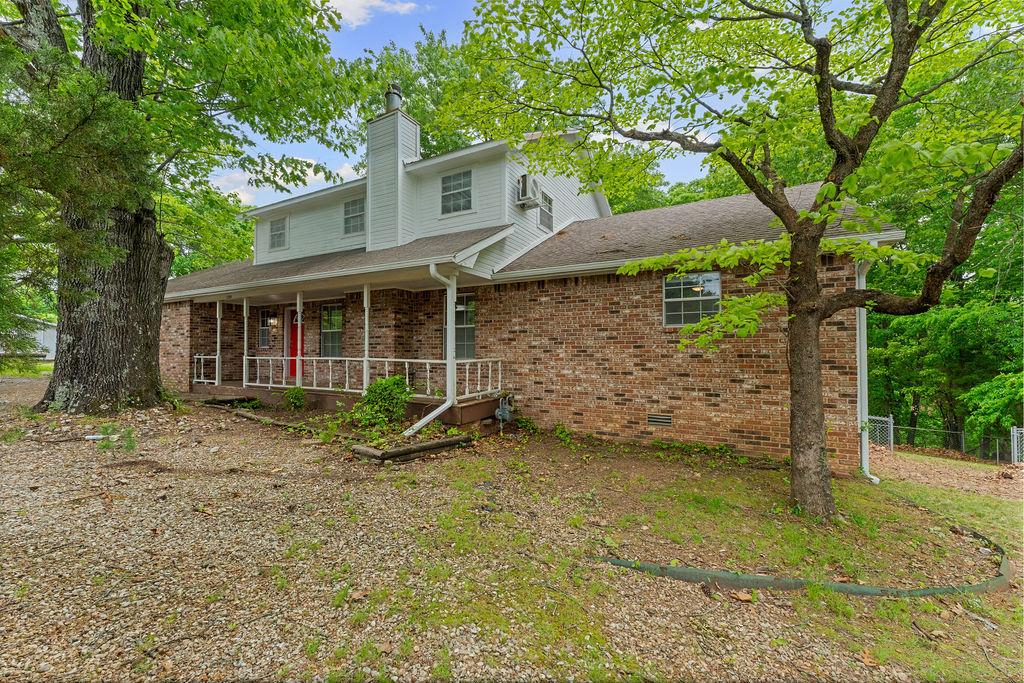 Image 1: Brick exterior with white siding and a covered fro
