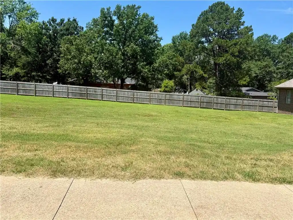 Image 1: Expansive grassy lot featuring a wooden privacy fe