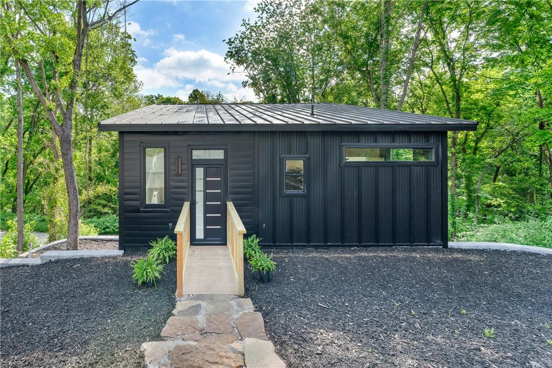 Image 1: Modern black exterior with a metal roof and board-
