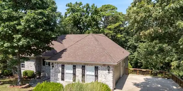 Image 2: Stone facade with dark shutters, shingled roof, tw