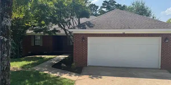 Image 3: Brick exterior with a shingle roof and an attached