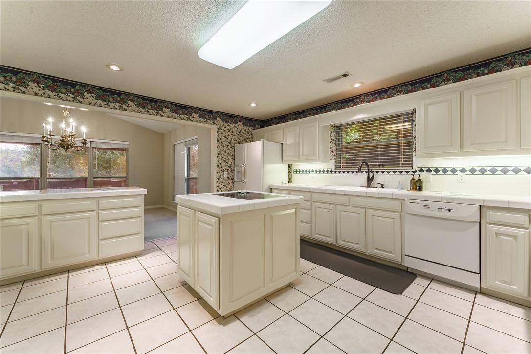 Image 4: Kitchen featuring an island, white cabinetry, tile