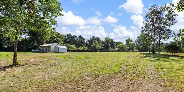 Image 2: Expansive grassy lot with mature trees
