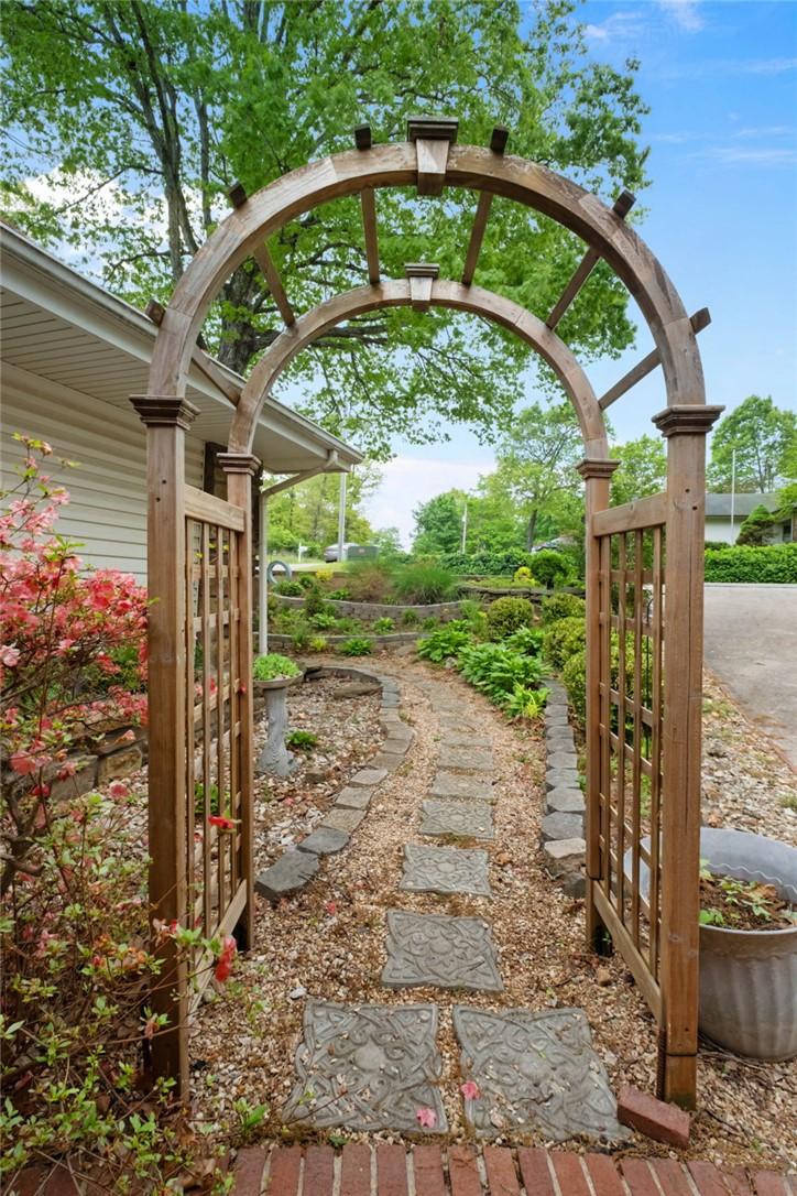 Image 4: Arched wood trellis entry to a stone-edged garden