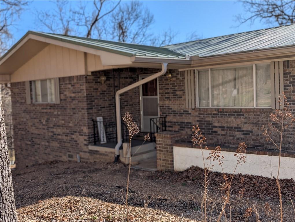 Image 3: Property entrance with brick siding and a metal ro