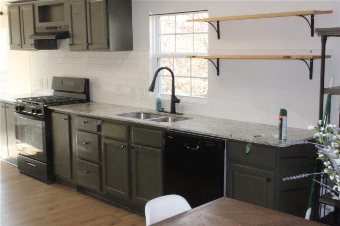 Image 3: Kitchen featuring gas range oven, open shelves, ta