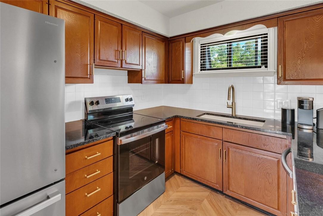 Image 3: Kitchen featuring wood cabinetry, stainless steel