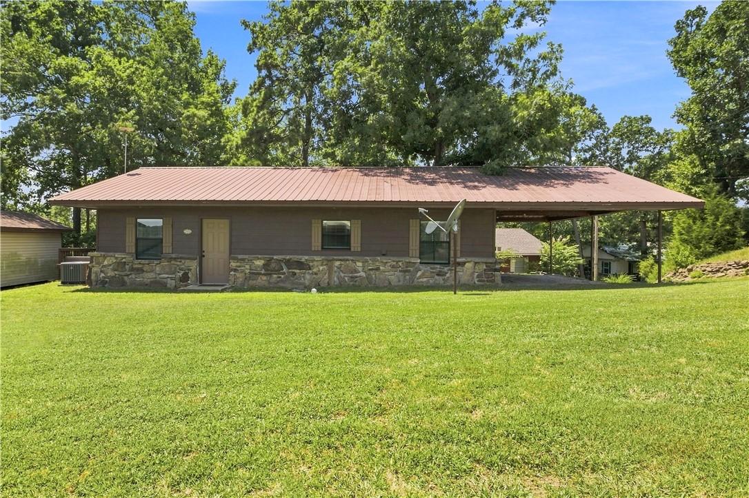 Image 1: Brown siding exterior with a metal roof and stone