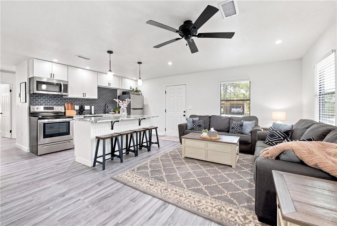 Image 4: Open concept living area featuring wood-finish flo