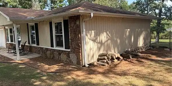 Image 2: Exterior featuring light-colored siding and a ston