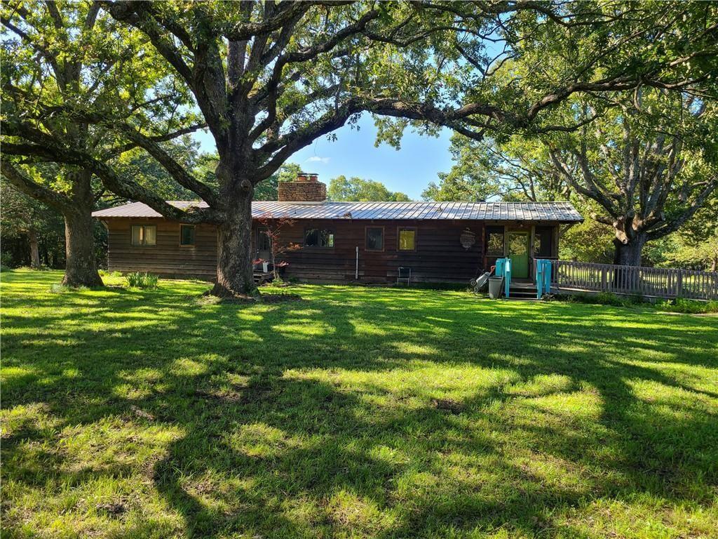 Image 1: Wood-sided home with a metal roof, featuring a bri