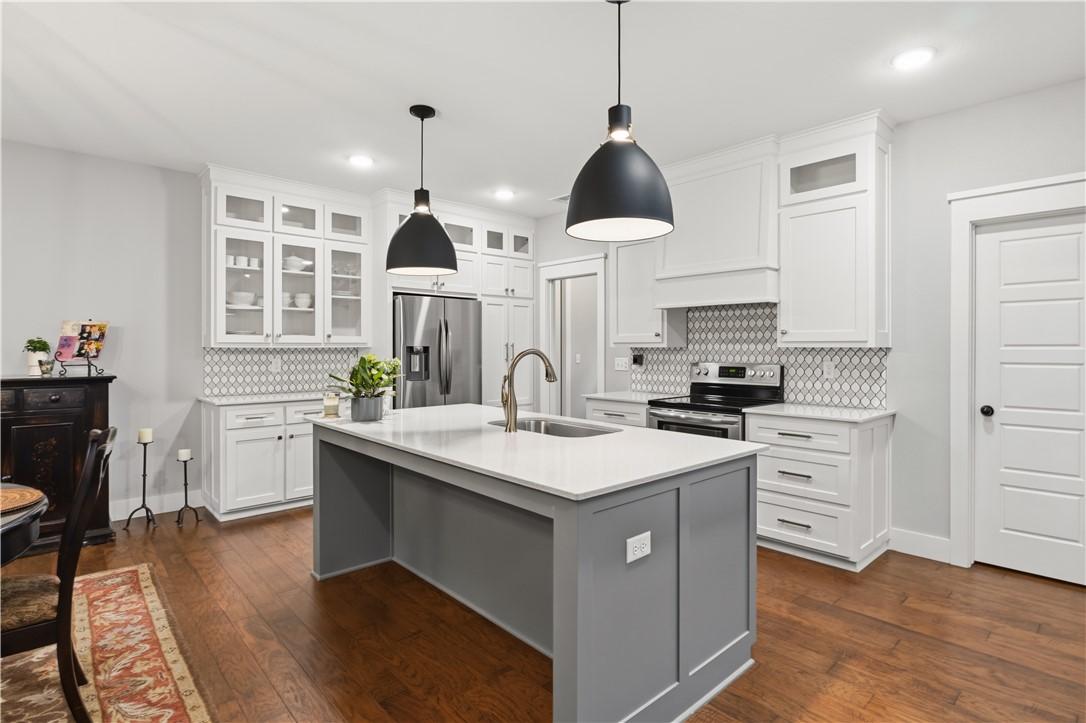 Image 4: The kitchen features hardwood floors, white cabine