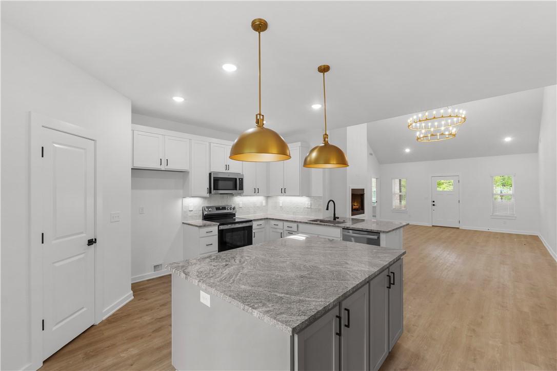 Image 4: The kitchen features an island with a light grey c