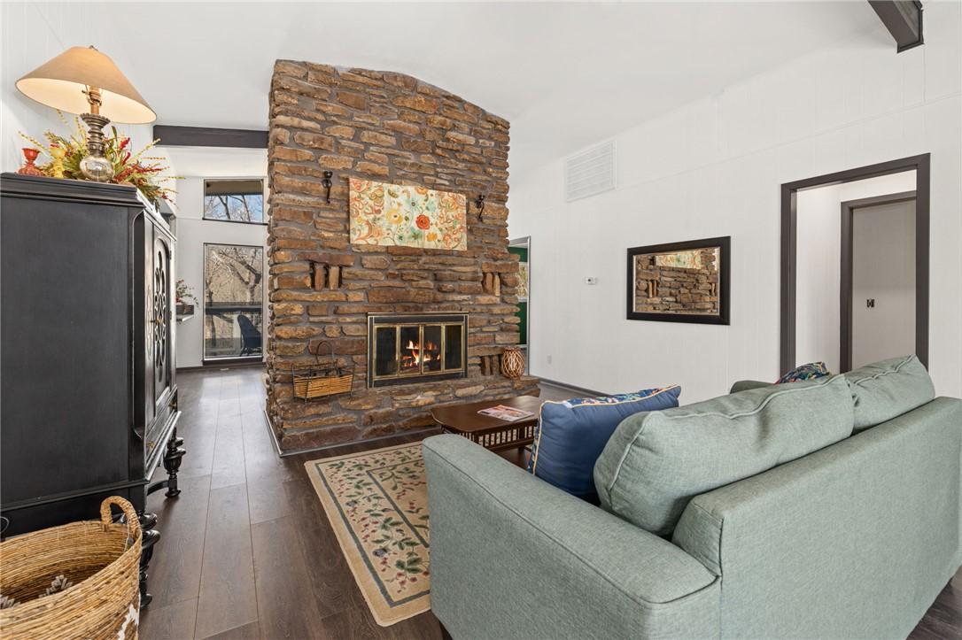 Image 3: Living area with dark wood-style floors and a ston