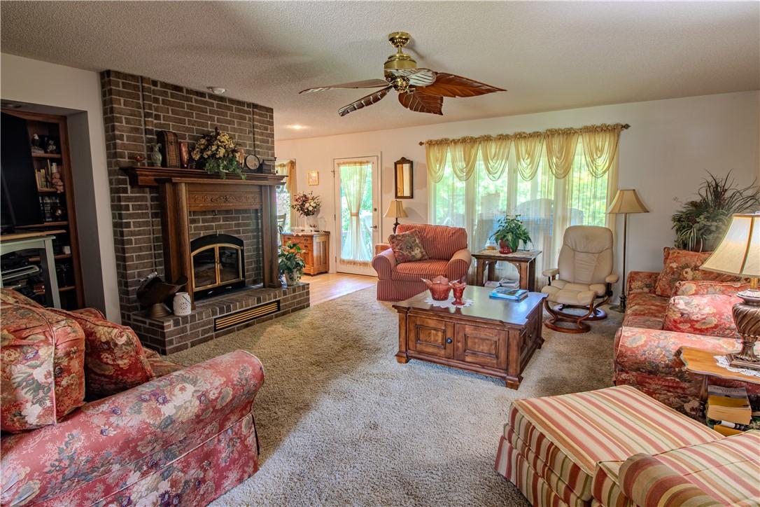Image 3: Living area featuring a brick fireplace with a woo