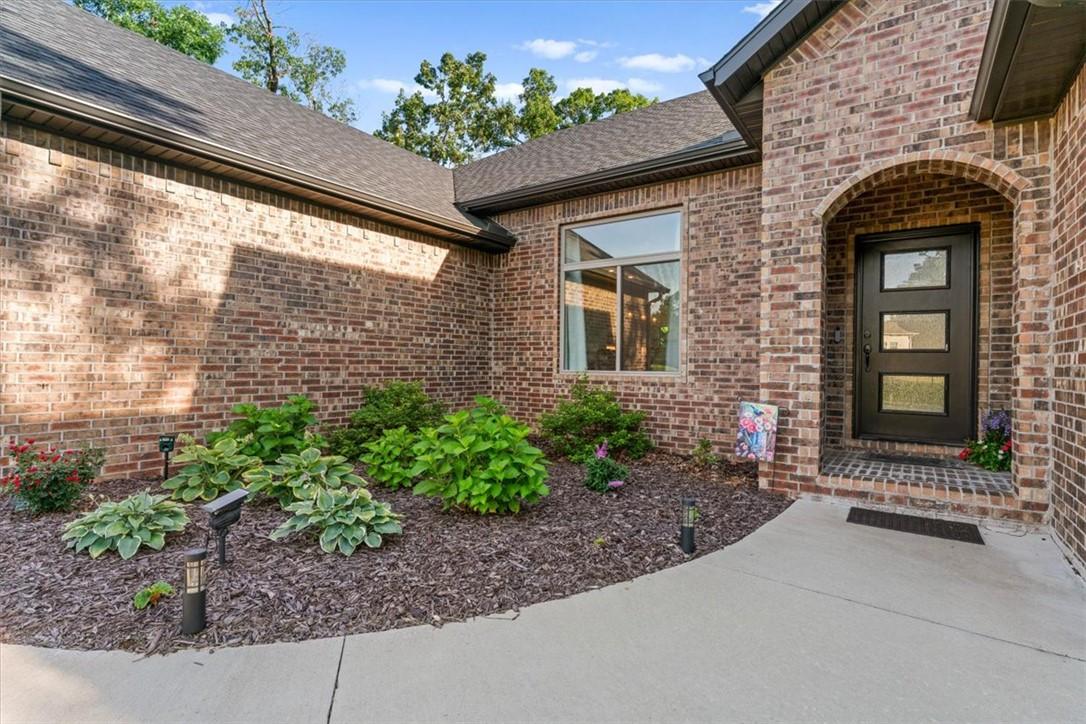 Image 2: Brick exterior featuring a dark entry door with th