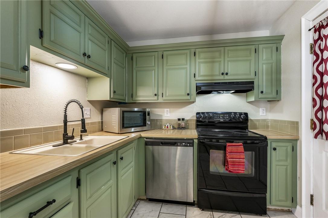 Image 4: Kitchen featuring green cabinetry, stainless steel
