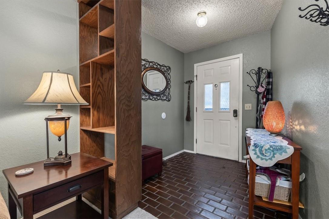 Image 4: Foyer with brick floors, a textured ceiling, and a