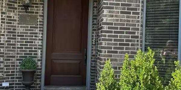 Image 3: Wood-finish entry door with multi-tone brick facad
