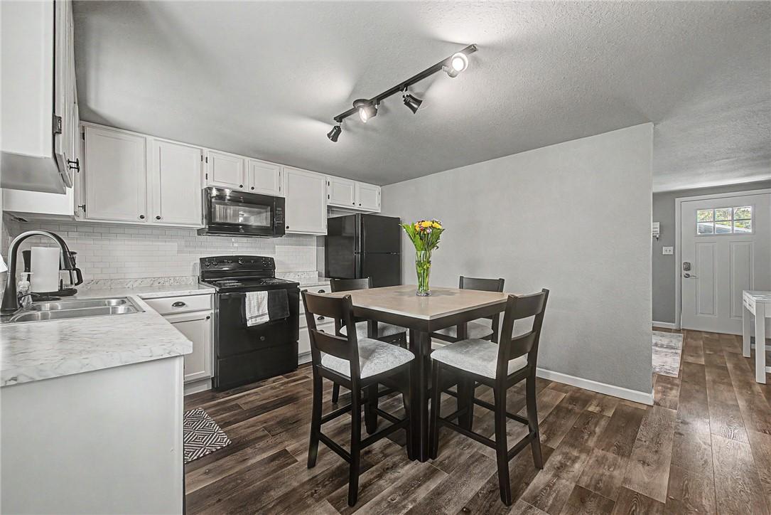 Image 4: Kitchen featuring white cabinetry with dark hardwa