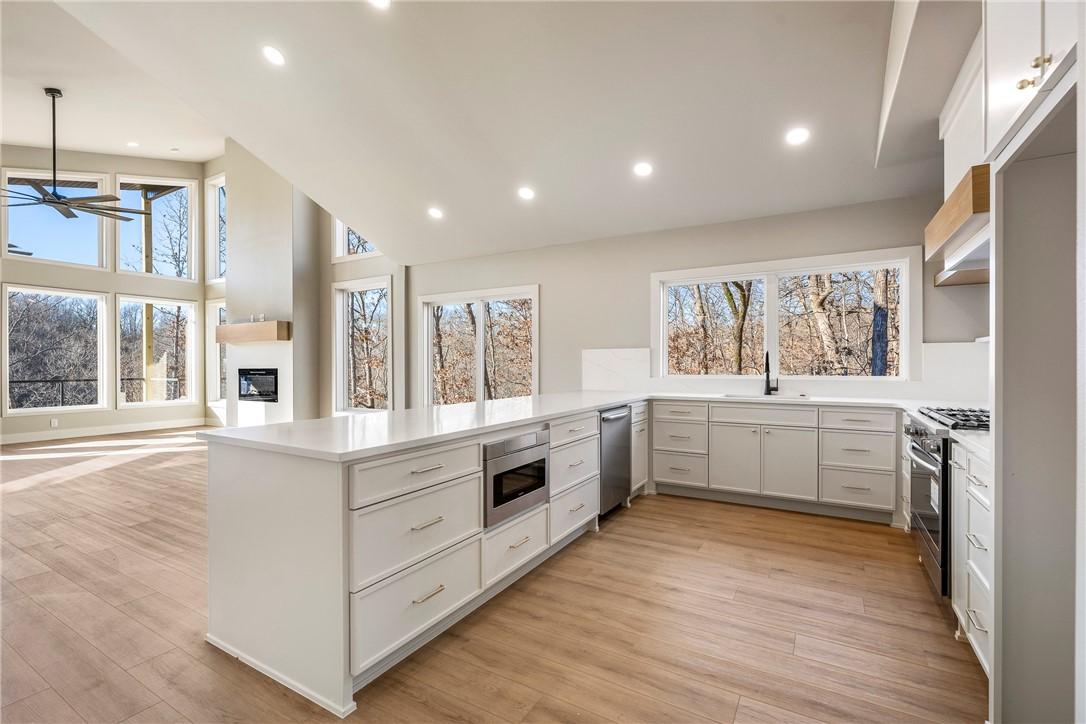 Image 3: Kitchen with white cabinets, a glass covered firep