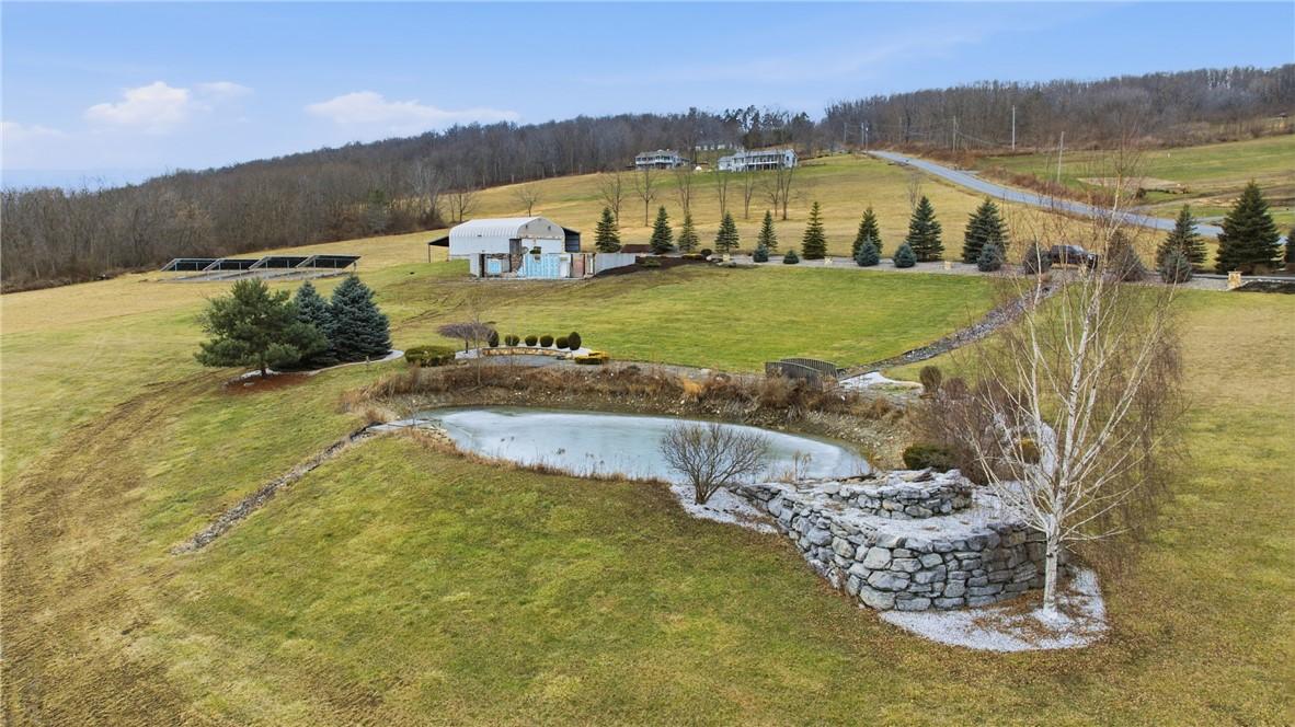 Image 2: Landscaped pond with waterside seating and waterfa