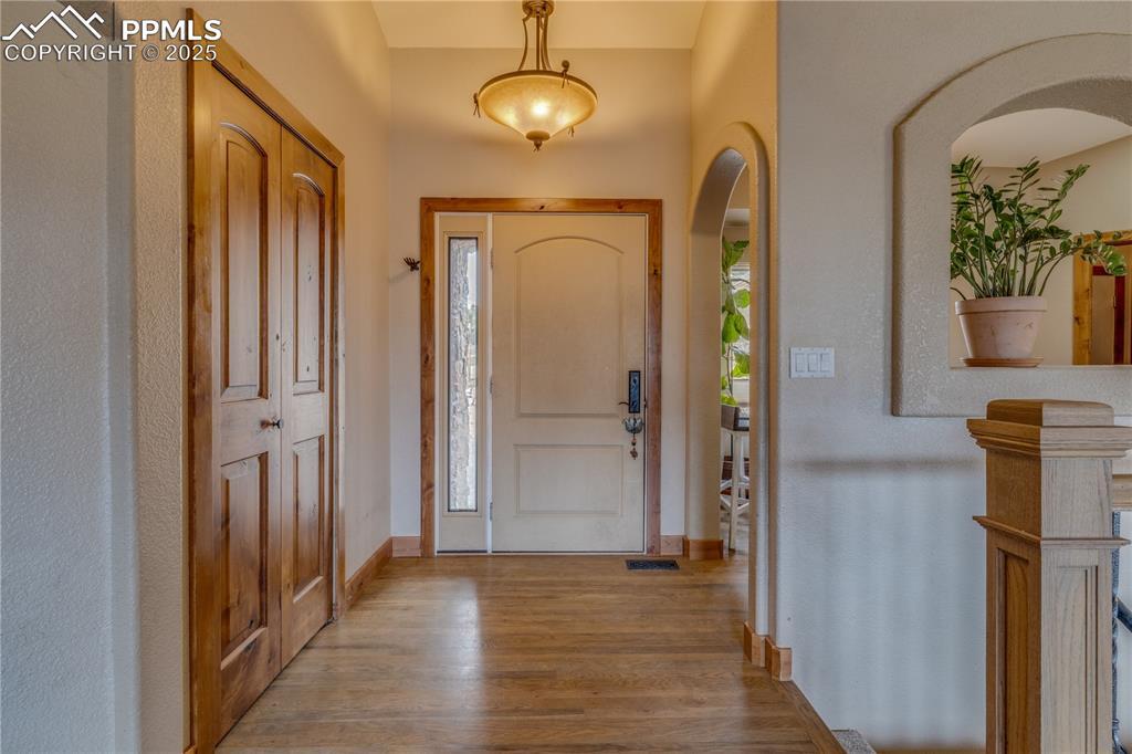 Image 3: Foyer entrance showcasing knotty alder wood doors and trim through out the main level, arched walkways beautiful hardwood flooring.