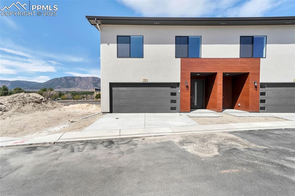 Image 1: Contemporary home featuring an attached garage, concrete driveway, a mountain view, and stucco siding