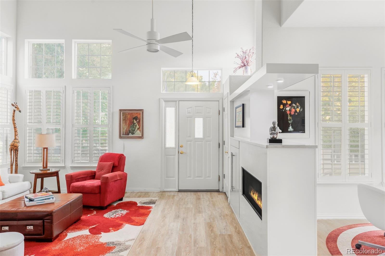 Image 3: Step into the living room, where soaring ceilings and expansive windows with custom louvered shutters fill the space with natural light, creating a warm and welcoming ambiance. Image 3: Step into the living room, where soaring ceilings and expansive windows with custom louvered shutters fill the space with natural light, creating a warm and welcoming ambiance.