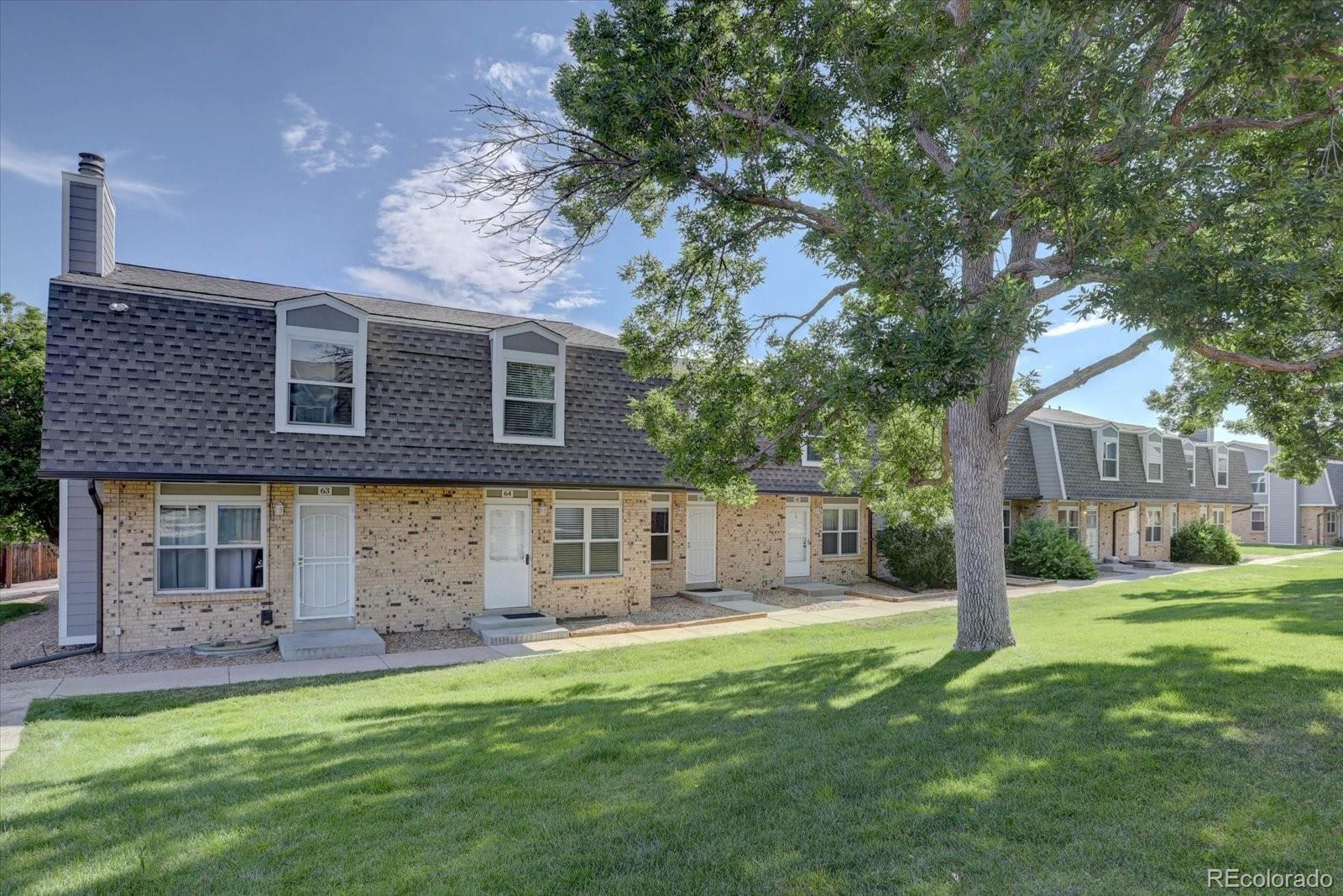 Image 2: Charming brick townhome community with well-kept green spaces, mature shade trees, and private front entrances offering a welcoming neighborhood feel.