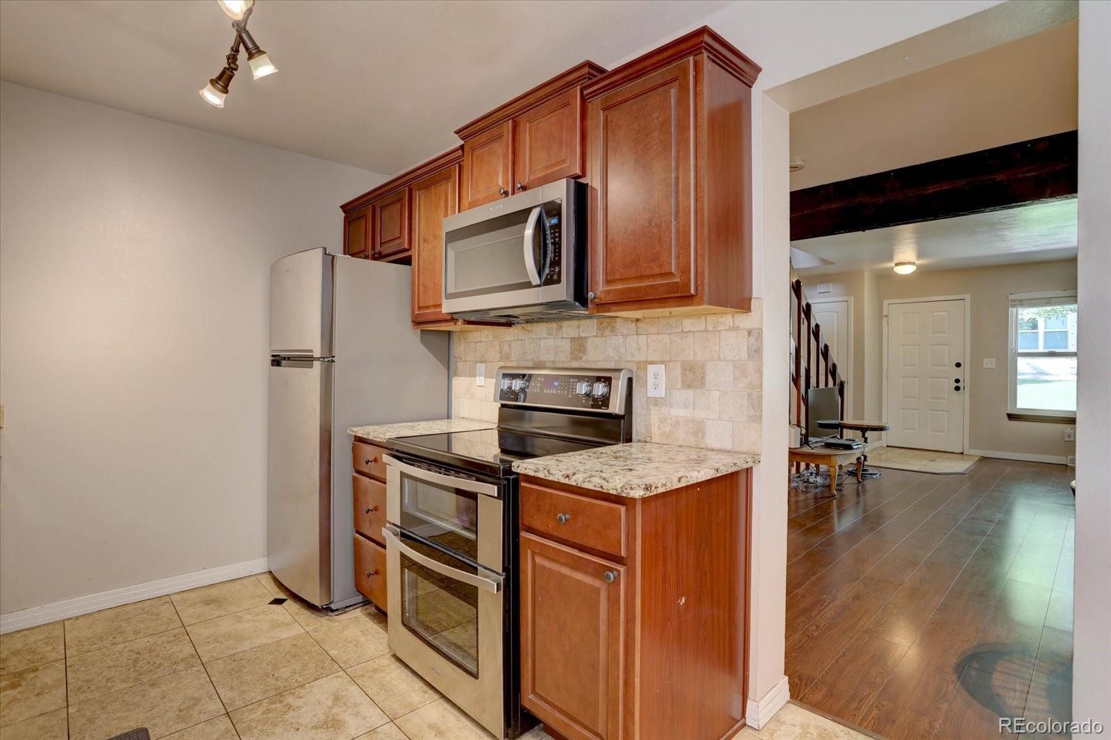 Image 4: Sleek stainless steel appliances and warm wood cabinetry flow seamlessly into the open living area, creating an inviting and functional main level layout.