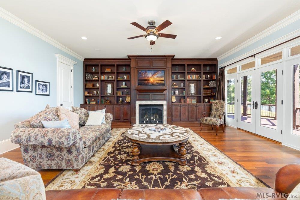 Image 4: Living Room, The spacious living room is centered around a stunning floor-to-ceiling custom wall unit, featuring wood cabinetry, integrated shelving, and a focal-point fireplace.