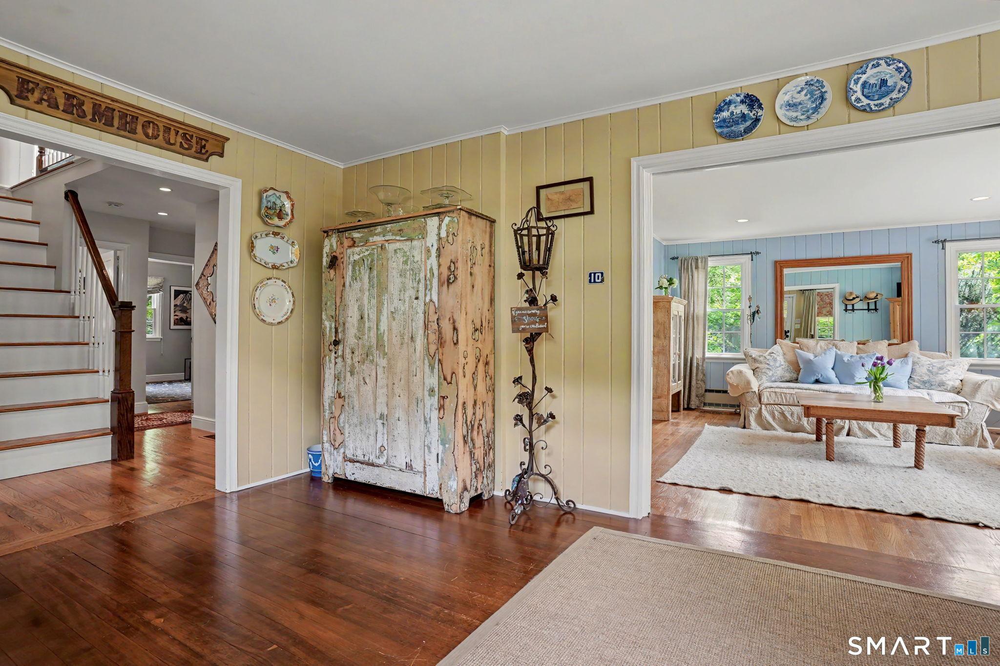 Image 4: Oversized foyer with gleaming hardwood floors. Open layout continues to the living room, with the dining room to the right.