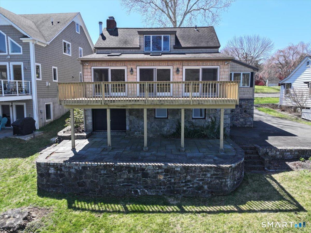 Image 2Back of House: Large Deck With Patio below accented by stone walls