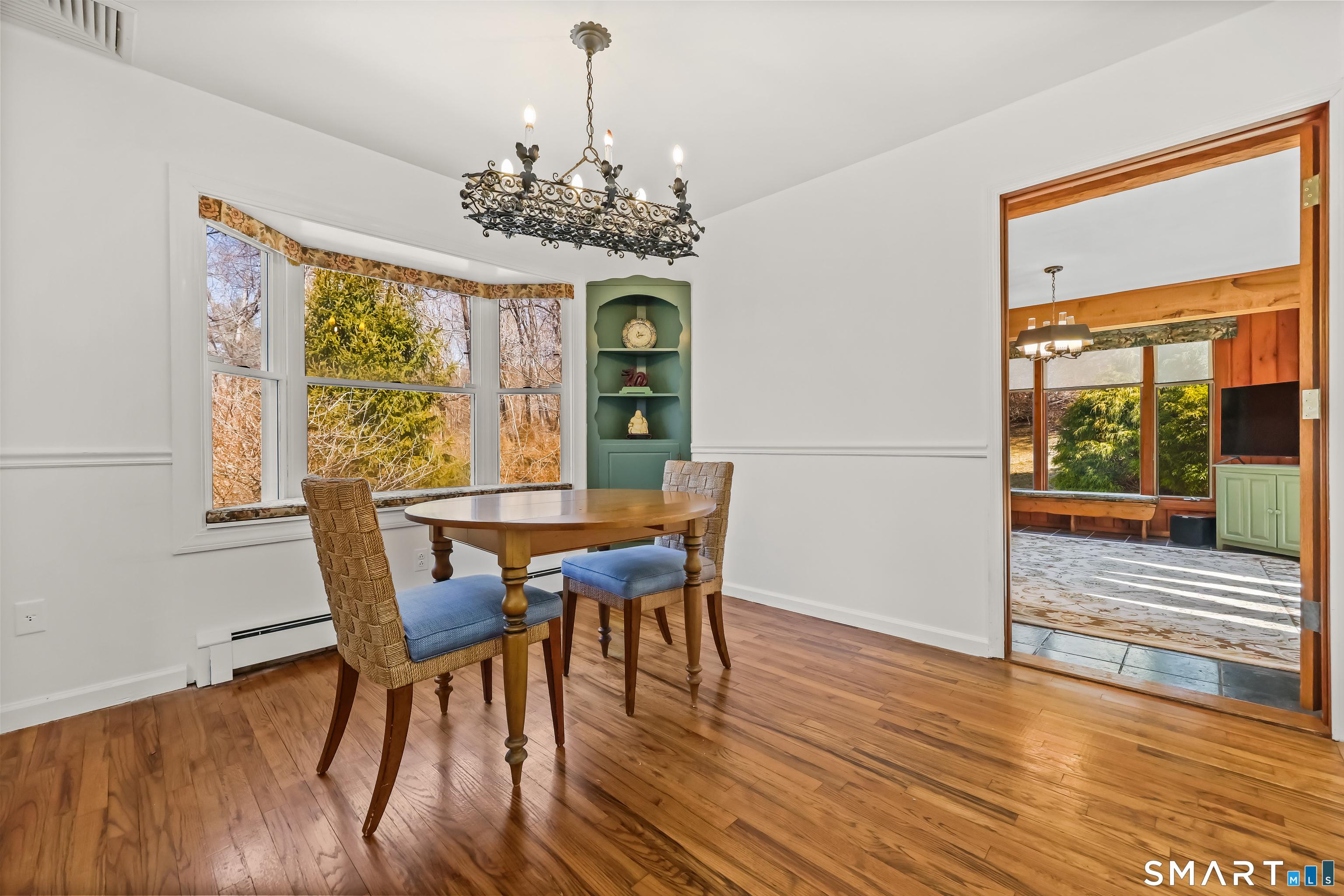 Image 4: Comfortable dining area that flows seamlessly into the kitchen, creating an ideal layout for everyday meals and casual entertaining. Hardwood floors and a charming built-in cabinet adds character and warmth.