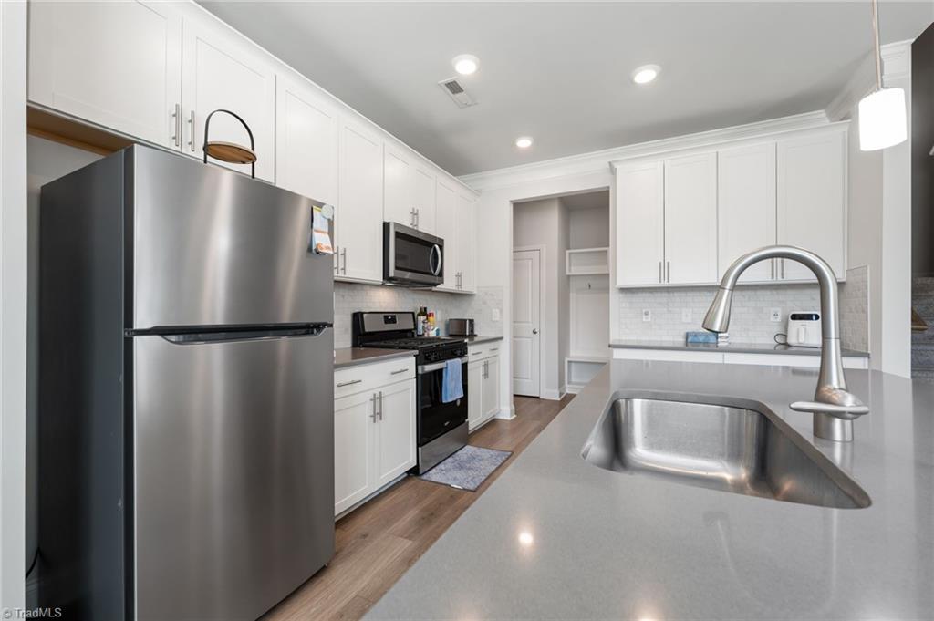 Image 4: Open kitchen with island, stainless steel appliances and quartz countertops on the main floor.