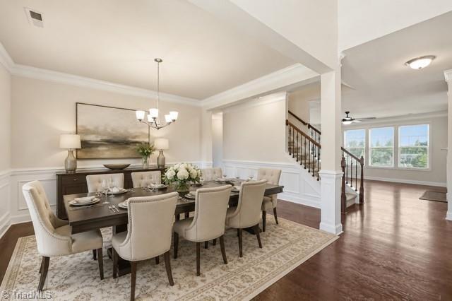 Image 3: Virtually staged formal dining room with hardwood floors, crown molding, and wainscoting.
