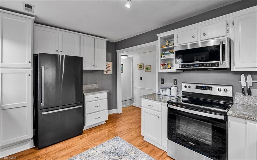 Image 3: Kitchen with white cabinetry, stainless appliances and quartz counters