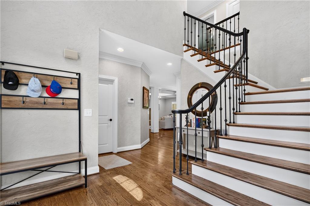Image 4: A two-story foyer welcome&mdash;curved staircase, hardwoods, and light pouring down.