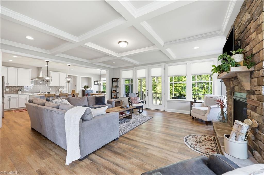 Image 4: Spacious open-concept living area featuring coffered ceilings and a striking stone fireplace.