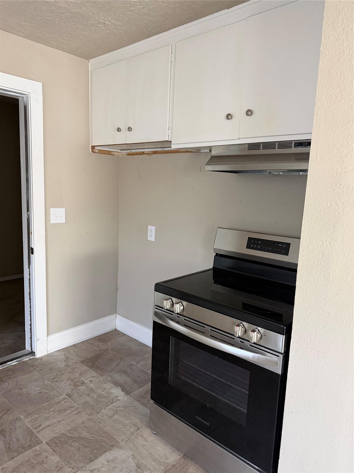 Image 4: Kitchen space featuring white upper cabinetry, a s
