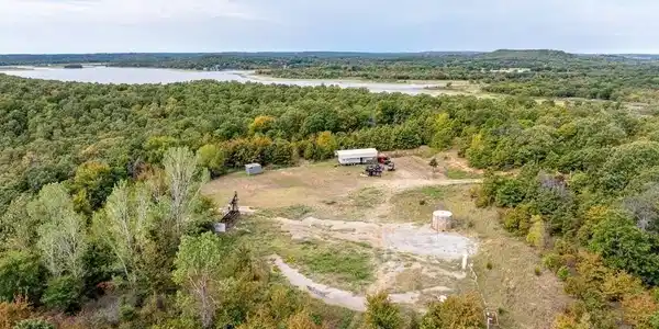 Image 2: Expansive wooded acreage with a cleared building s