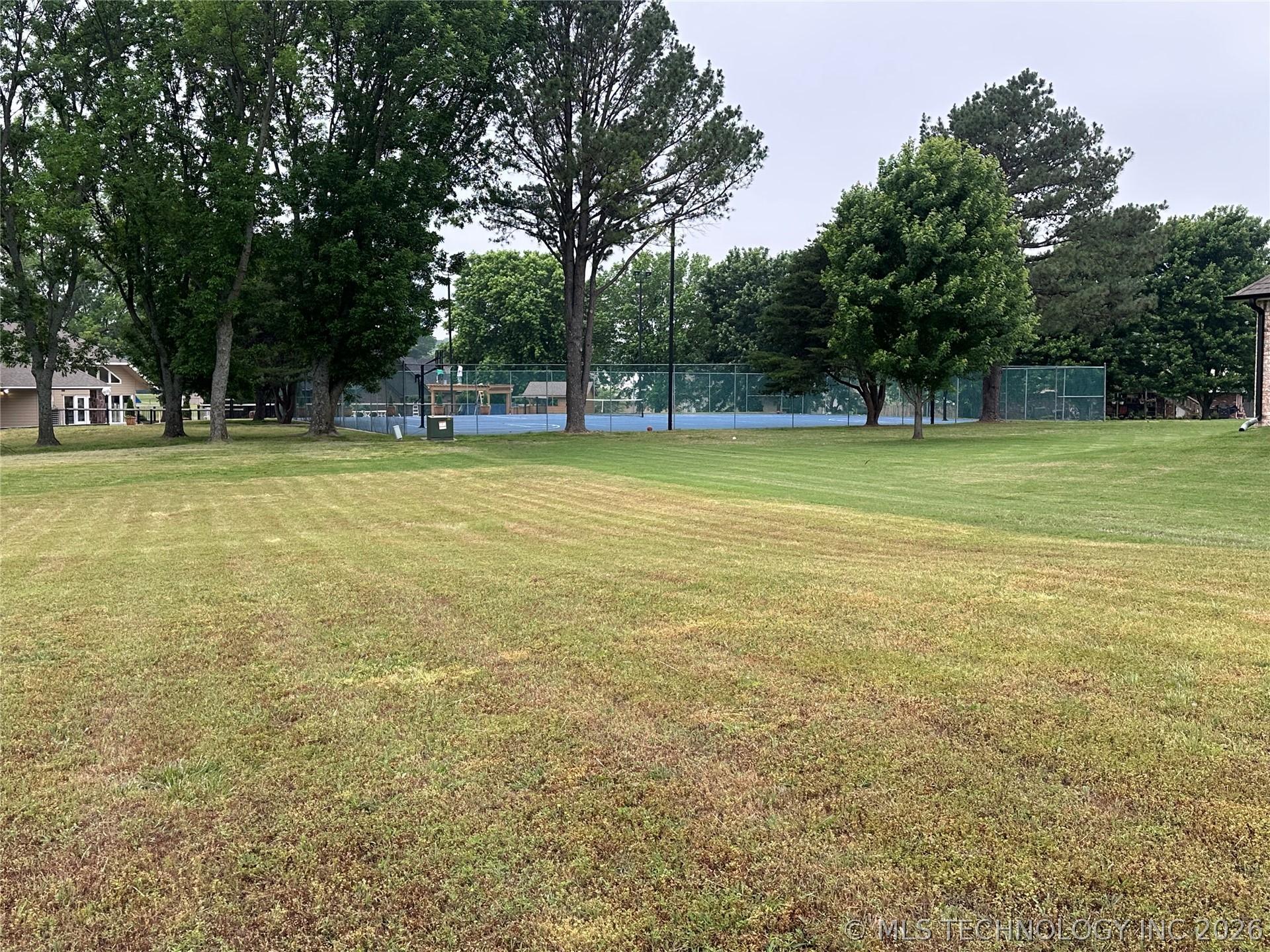 Image 2: Expansive green space featuring a clear tennis cou
