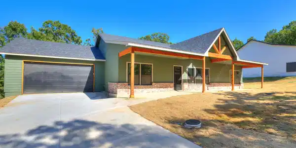 Image 2: Exterior featuring green siding, dark gray roofing